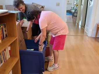 An LCS participant is helping an employee sort books at a volunteer site.