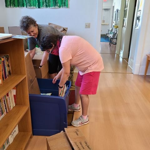 An LCS participant is helping an employee sort books at a volunteer site.